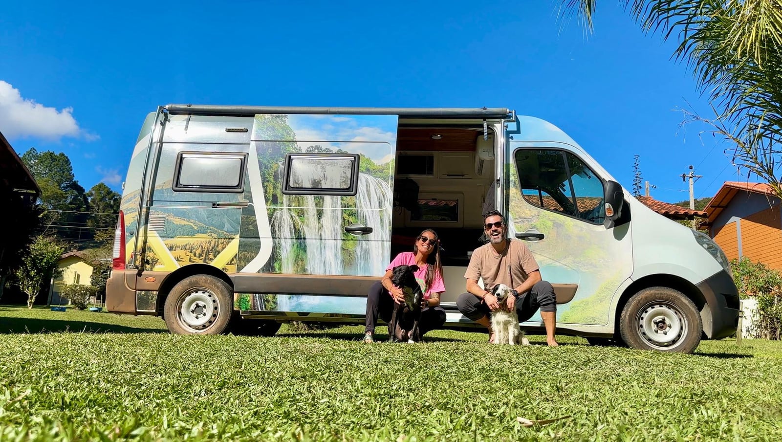 Thaíssa, Julián, Bali e Vândalo sentados na grama, na frente do motorhome alugado